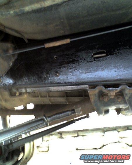 Underbody view of vehicle suspension with cable and Supermotors.net watermark