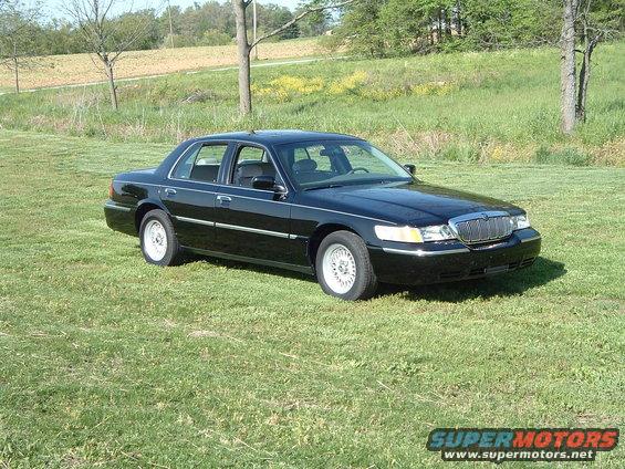 Black 2001 Mercury Grand Marquis sedan parked on grass, front 3/4 view