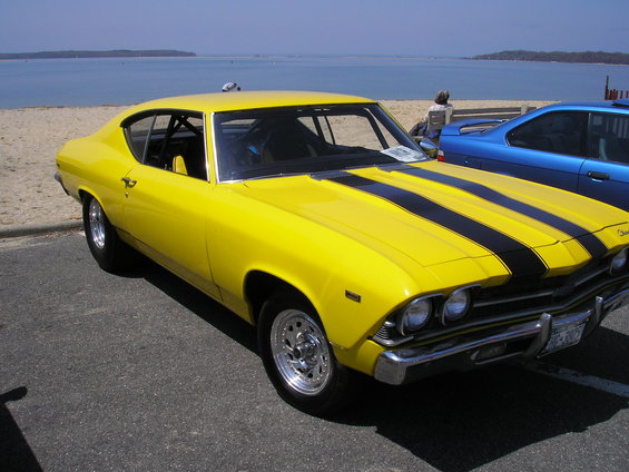 Yellow 1969 Chevrolet Chevelle SS coupe with black racing stripes parked by a beach
