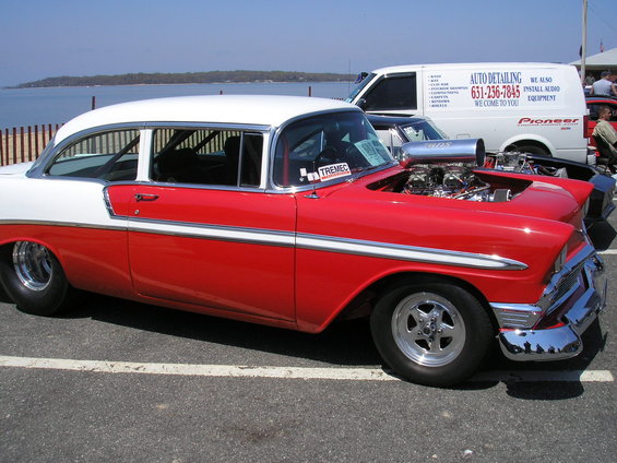 Red and white sedan with exposed engine and drag slicks. 1956 Chevrolet