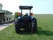 1984 Honda ATC 250 R - Rear view of a blue tractor with large tires and a canopy, situated on a grassy lawn next to a residential building.