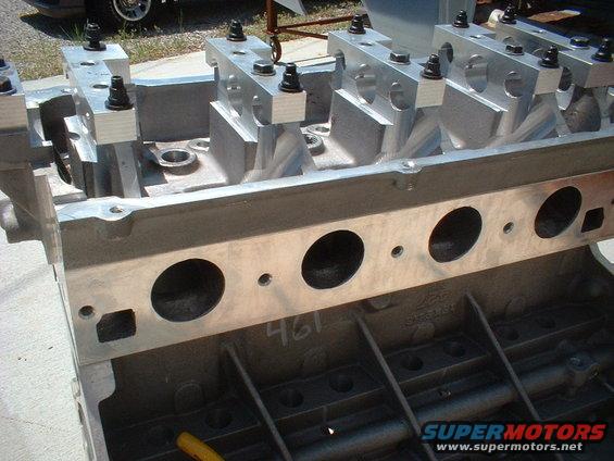 Close-up of an engine block with aluminum heads bolted on, showing intake ports