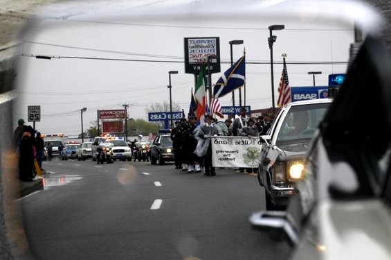 Parade scene with police escort, flags, and a banner reading 'Preserving the Tradition'