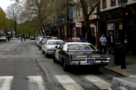 Several police cars parked on a street, one in foreground says HIGHWAY PATROL