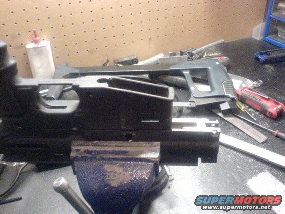 Black gun receiver clamped in a blue vise on a workbench with tools