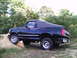 1995 Ford Bronco - This black 1995 Ford Bronco features a removable soft top and is shown navigating an off-road incline.