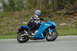 2007 Kawasaki Ninja R - A rider on a blue 2007 Kawasaki Ninja R motorcycle is seen from the side on a paved road.