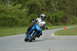 2007 Kawasaki Ninja R - Motorcycle rider navigates a turn on a paved track with grassy shoulders and trees in the background.