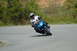2007 Kawasaki Ninja R - Motorcyclist takes a corner on a sunny day, with trees and foliage in the background.