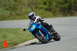 2007 Kawasaki Ninja R - A motorcycle rider takes a corner on a paved track with grass and trees in the background.