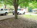 1977 Ford F-100 - A white 1977 Ford F-100 pickup truck with a camper shell is parked in a driveway, with other vehicles visible.