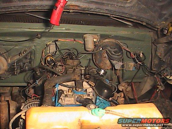Engine bay with V8 engine, carburetor, and hoses. Green painted firewall