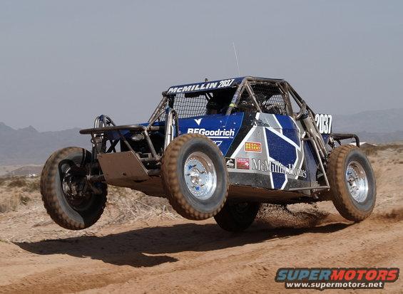 Off-road buggy with 'McMillan 2037' and 'BFGoodrich' decals airborne over dirt