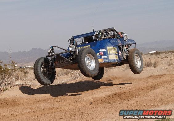 Blue off-road buggy airborne over dirt track