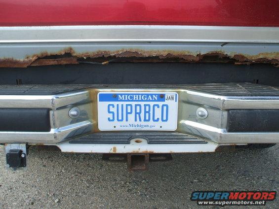 Rear bumper with Michigan license plate reading SUPRBC0, showing rust on the body panel above