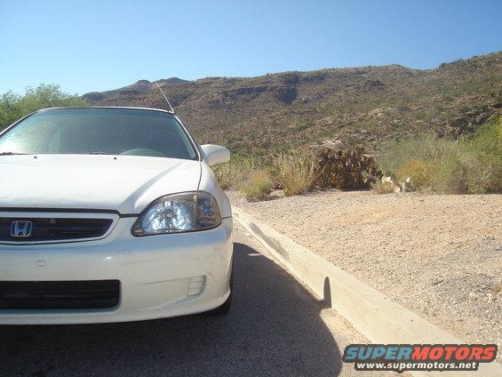 White Honda parked on gravel with desert hills in background