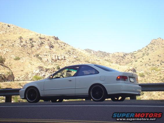 White 1999 Honda Civic coupe parked on the side of a road with mountains in the background