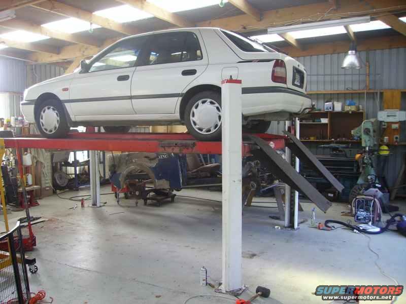 White sedan on a car lift, side view