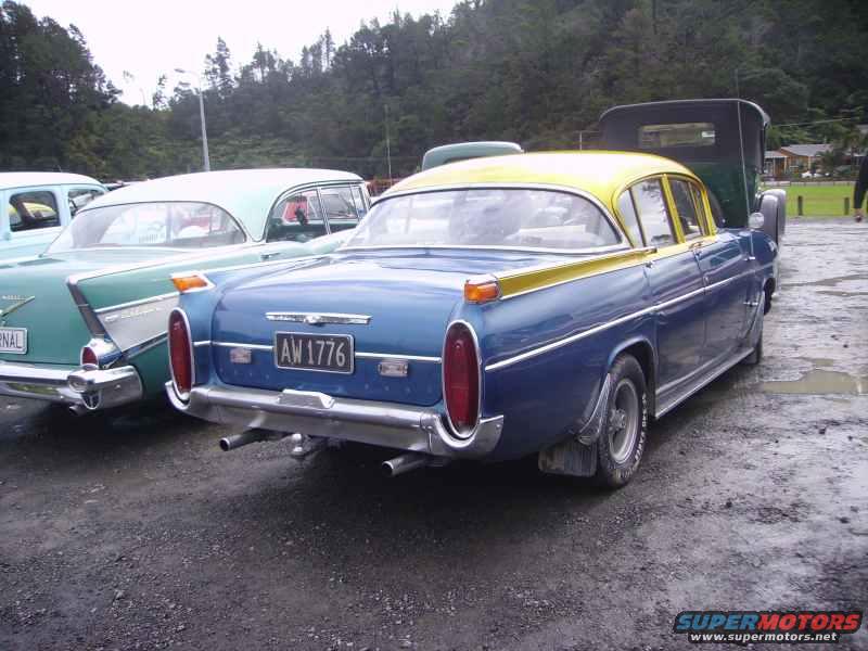 Rear view of a blue sedan with a yellow roof parked next to a teal car. License plate reads AW 1776