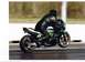 1999 Kawasaki H2C - A motorcycle rider in full leather gear executes a wheelie on a race track, with blurred background indicating speed.