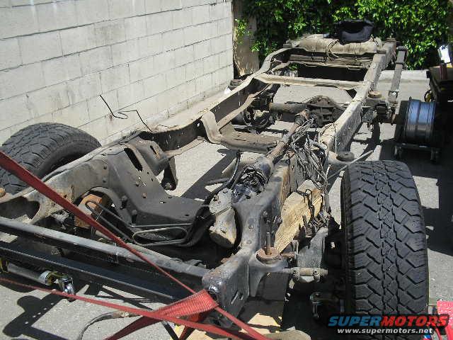 Truck chassis with frame, suspension, and tires visible. A spare wheel is on a cart