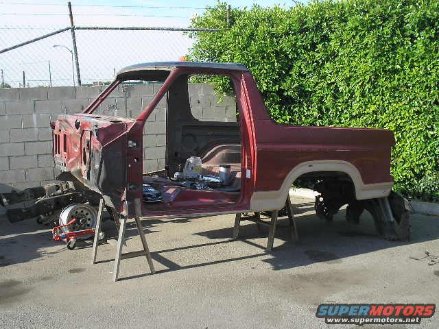 Red 1980s Ford Bronco body shell on sawhorses, front end removed
