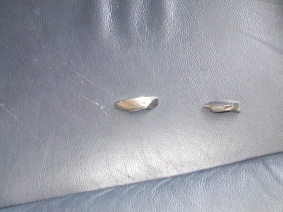 Two metal fragments on blue leather upholstery