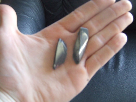 Two dark gray broken plastic fragments held in a palm