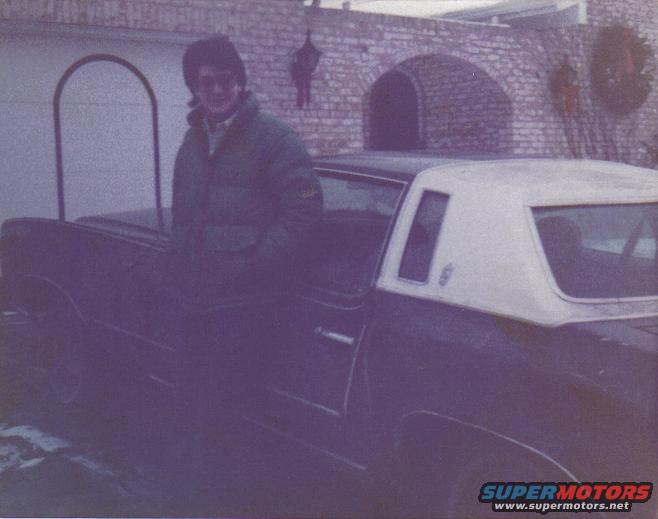 man in green jacket leaning on dark car with white vinyl roof