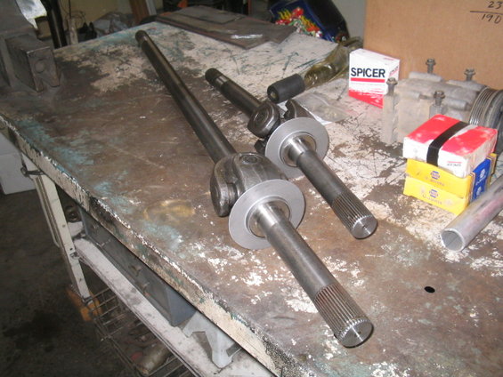Two axle shafts with U-joints and Spicer boxes on a workbench