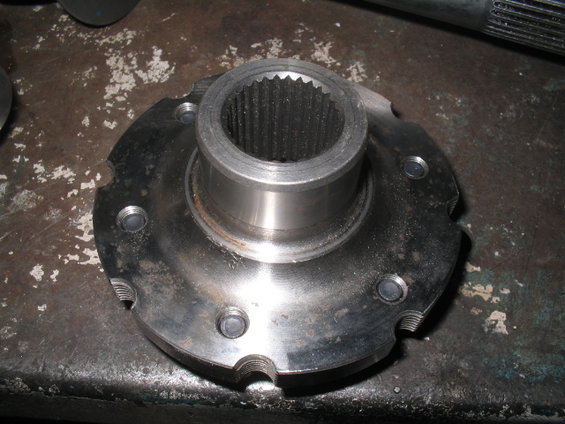 Metal wheel hub part with splines and bolt holes on a workbench