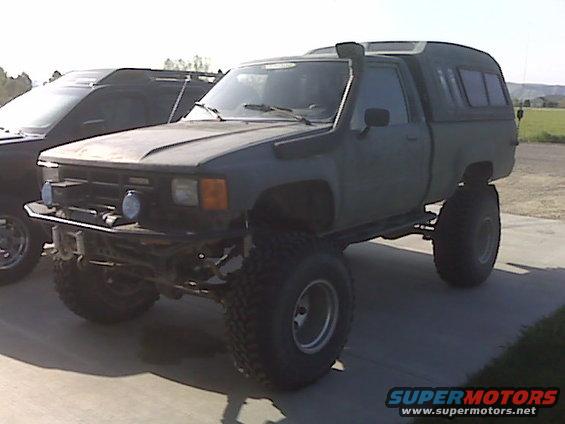 Gray lifted 1985 Toyota Hilux pickup truck with snorkel and camper shell