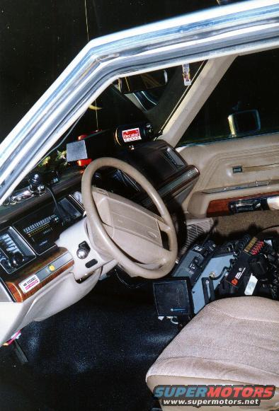 Interior of a 1991 Ford Crown Victoria police car, showing steering wheel, dashboard, and mounted equipment