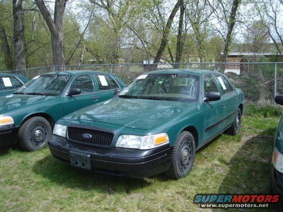 Green Ford Crown Victoria, parked outside with other similar cars