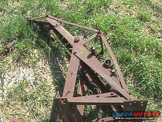 Rusted metal farm equipment part lying in grass