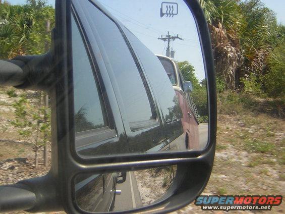 Side mirror reflection of a red and white van
