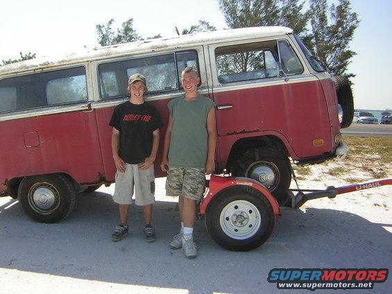 1971 Volkswagen Vanagon, red and white, with two boys standing next to it and a U-Haul trailer attached