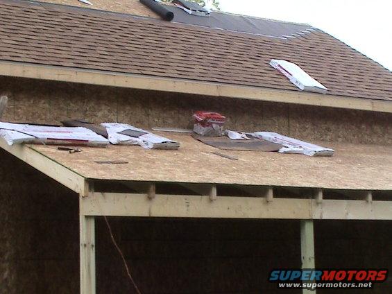 Roof under construction with shingles, plywood, and building materials laid out