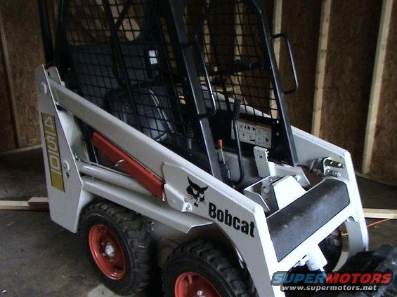 White Bobcat skid steer loader with orange rims, side view