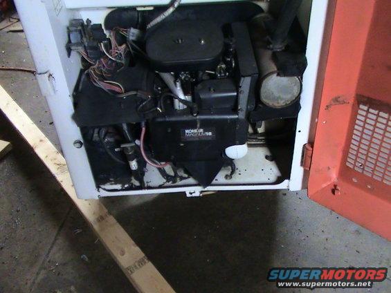 Open engine compartment of a white and orange machine, showing a Kohler Magnum engine and wiring