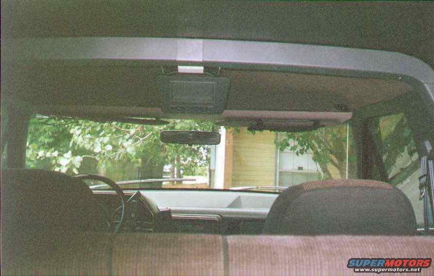 Car interior with fabric seats, steering wheel, and dashboard visible through the windshield