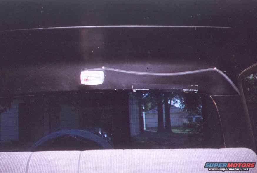 Interior overhead light fixture and rear window view of trees and houses