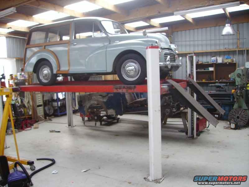 Light blue wood-paneled station wagon on a red car lift, front 3/4 view, in a garage