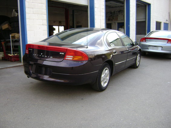 Dark purple Dodge Intrepid sedan, rear 3/4 view, parked in front of garage bays