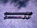 1987 Ford Bronco II - Two driveshafts are shown side-by-side on a gravel surface.