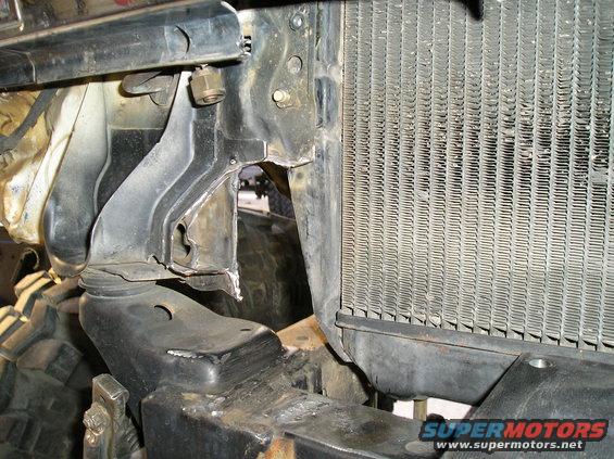 Modified black metal brackets attached to a radiator and vehicle frame
