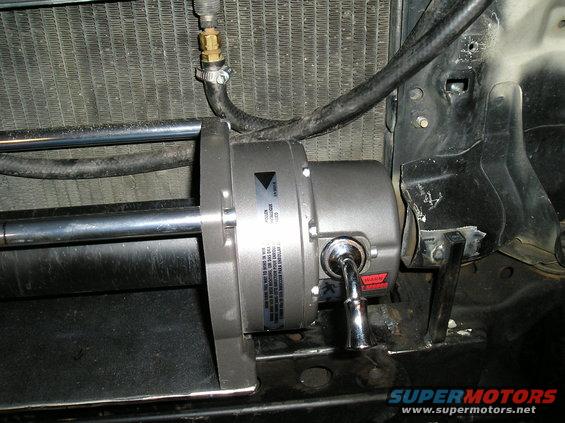 Winch mounted in front of a radiator with visible hoses and mounting brackets
