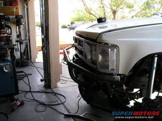 Front bumper and fender of a white truck with a custom brush guard. Visible Bilstein shock absorber
