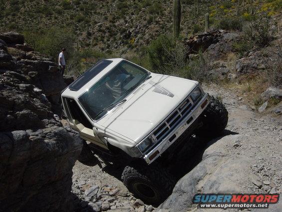 White 1986 Toyota Hilux off-roading on rocks
