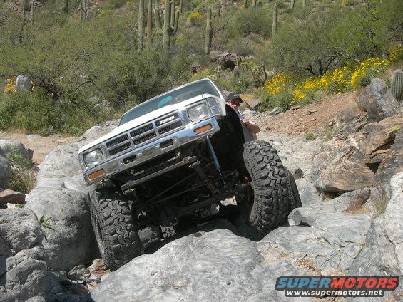 White 1986 Toyota pickup truck navigating rocky terrain